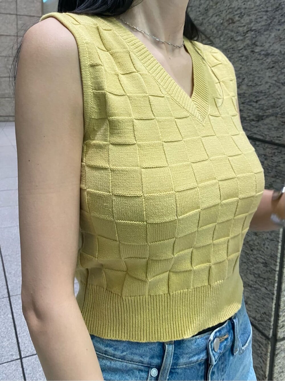 イエロー系のタンクトップ、ブルー系のデニムパンツ、ブラック系のサンダルを着用したレディースの夏コーディネートの5枚目の写真