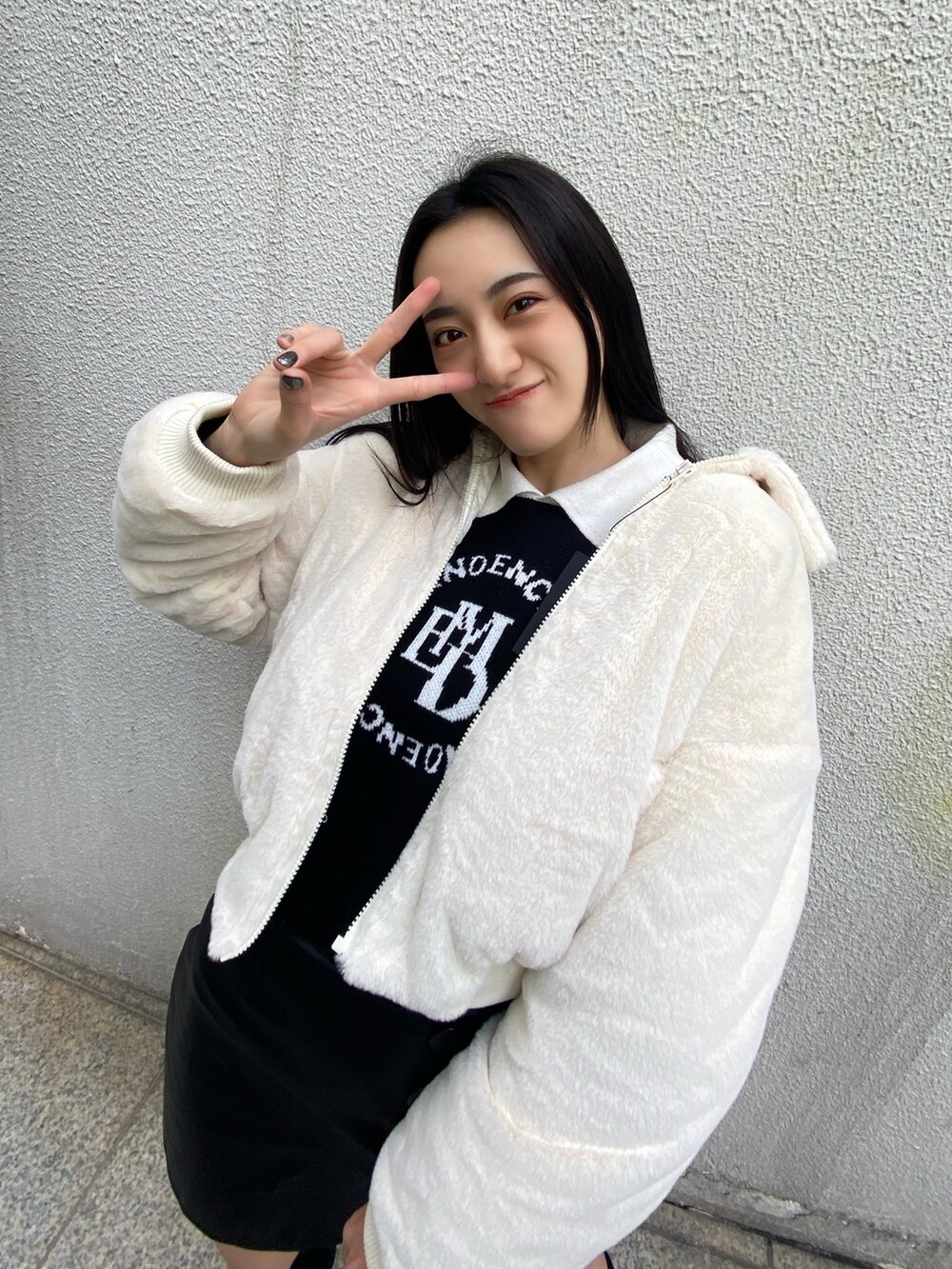 ブラック系のニット/セーター、ホワイト系のブルゾン、その他のスカートを着用したレディースの秋コーディネートの5枚目の写真