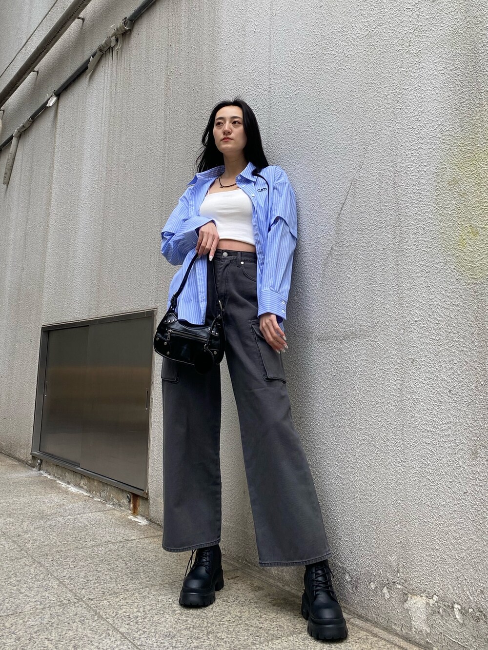 ブラック系のデニムパンツ、ブラック系のハンドバッグ、ブラック系のブーツを着用したレディースの春コーディネートの2枚目の写真