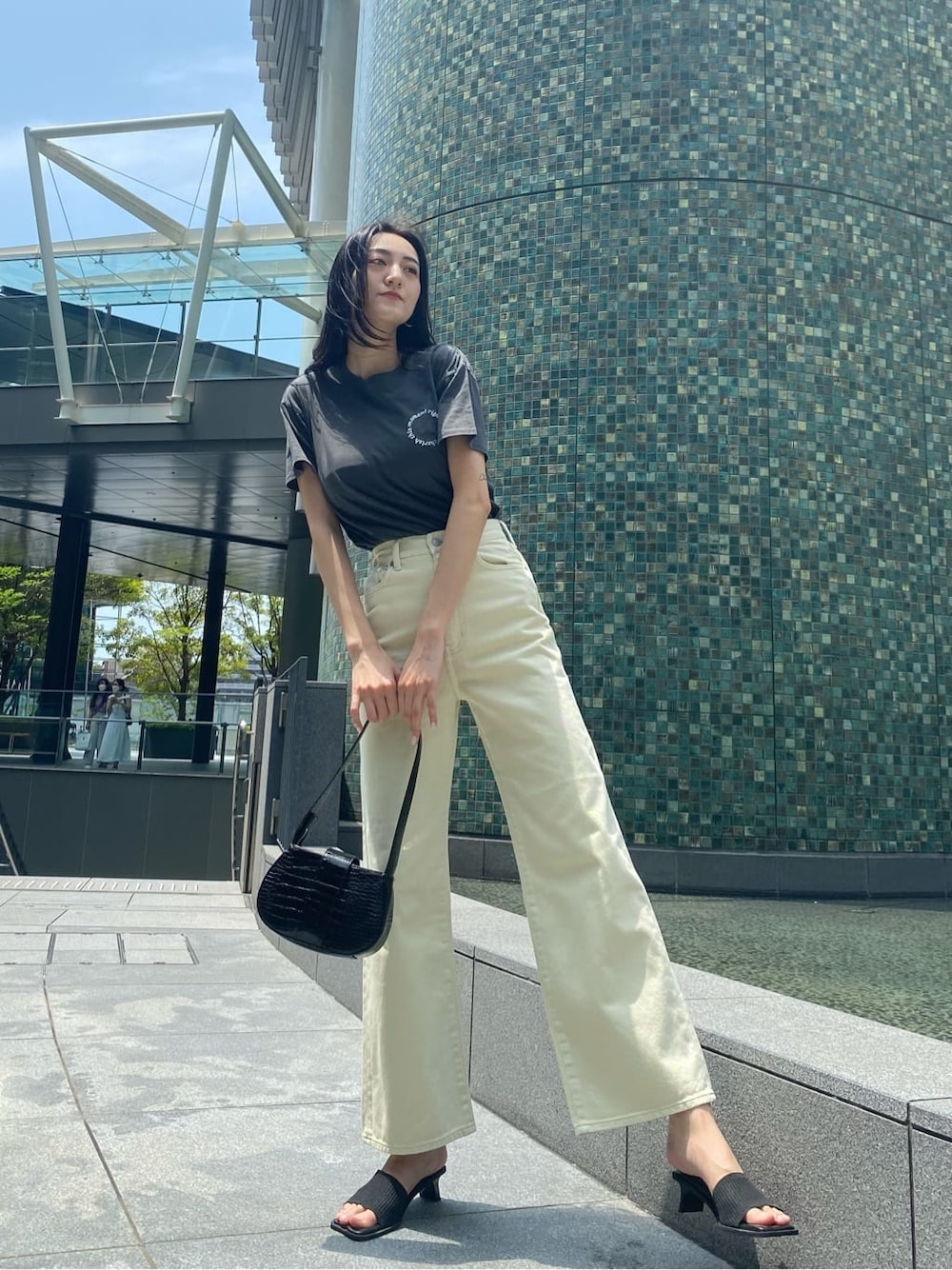 ホワイト系のデニムパンツ、ブラック系のサンダル、ブラック系のハンドバッグを着用したレディースの夏コーディネートの3枚目の写真