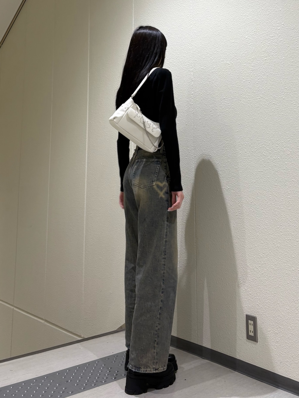 ブラック系のブーツ、ブルー系のデニムパンツ、ホワイト系のハンドバッグを着用したレディースの春コーディネートの3枚目の写真