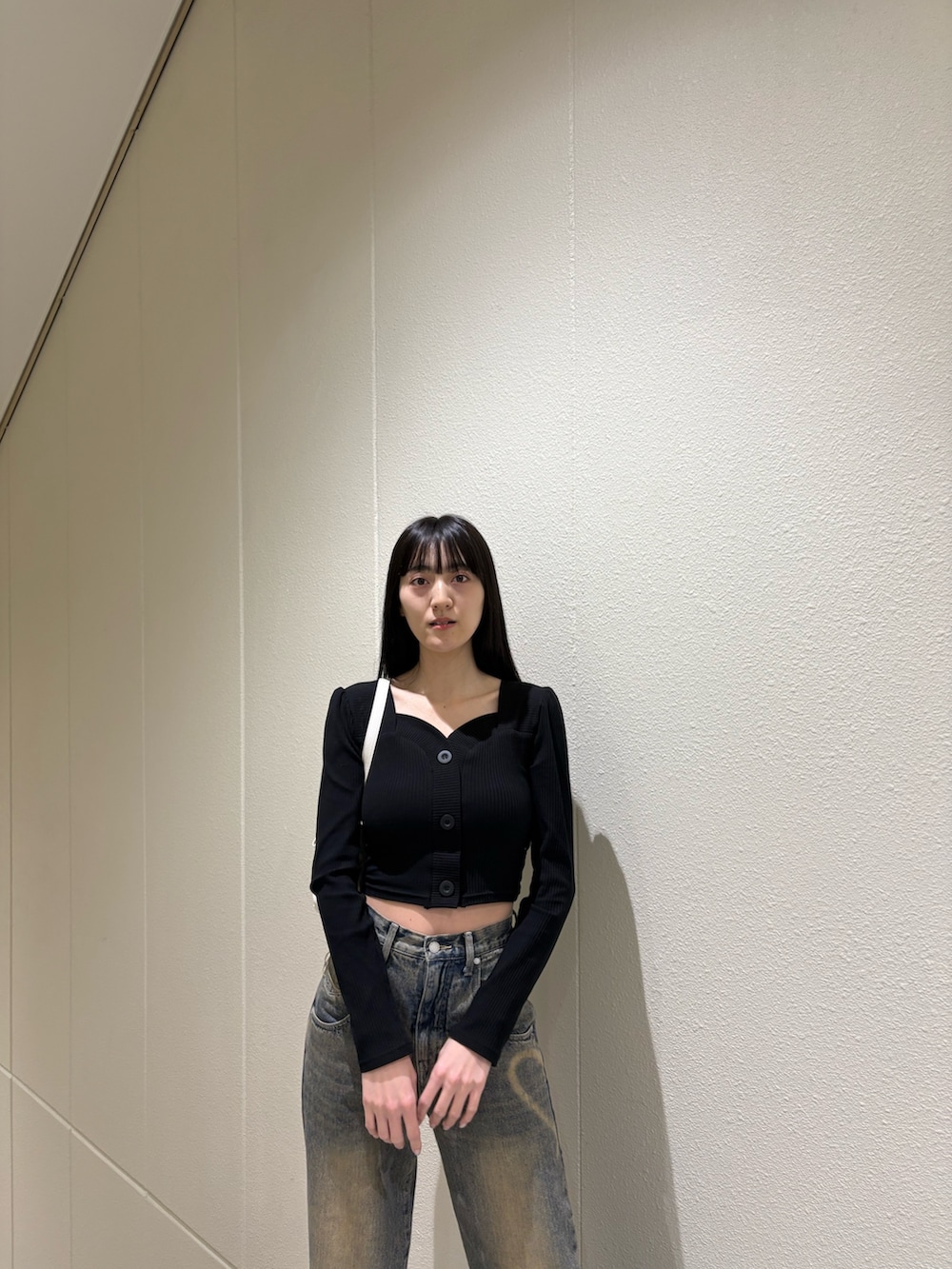 ブラック系のブーツ、ブルー系のデニムパンツ、ホワイト系のハンドバッグを着用したレディースの春コーディネートの6枚目の写真