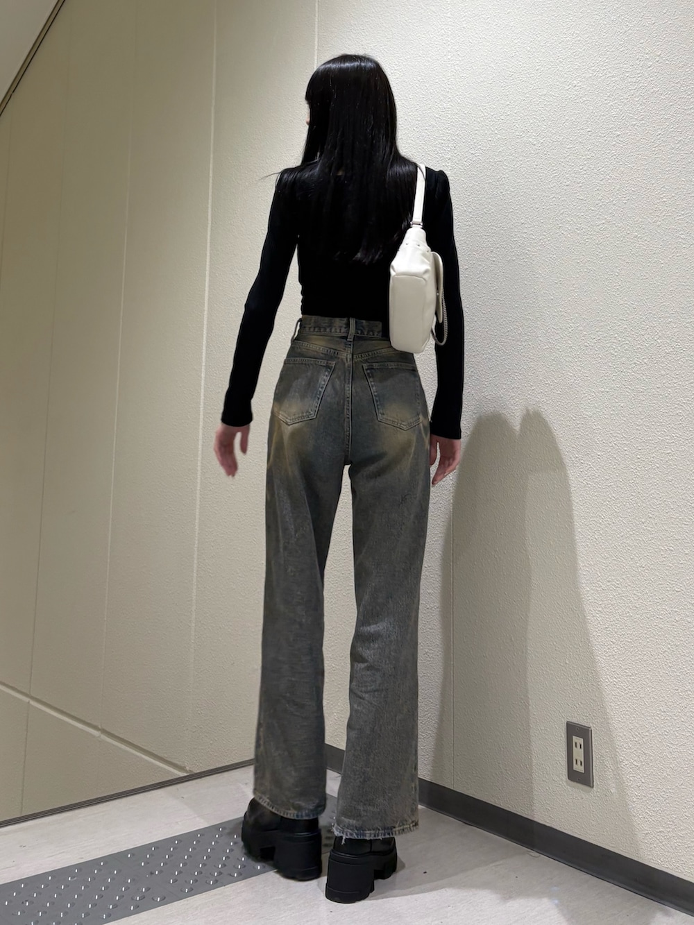 ブラック系のブーツ、ブルー系のデニムパンツ、ホワイト系のハンドバッグを着用したレディースの春コーディネートの4枚目の写真