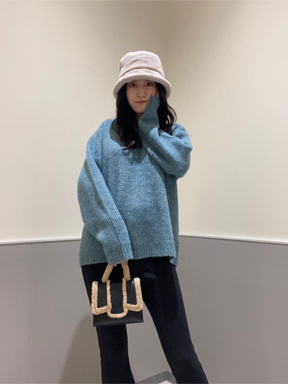 ブラック系のハンドバッグ、ブルー系のニット/セーター、ブラック系のその他パンツを着用したレディースの秋コーディネートの4枚目の写真