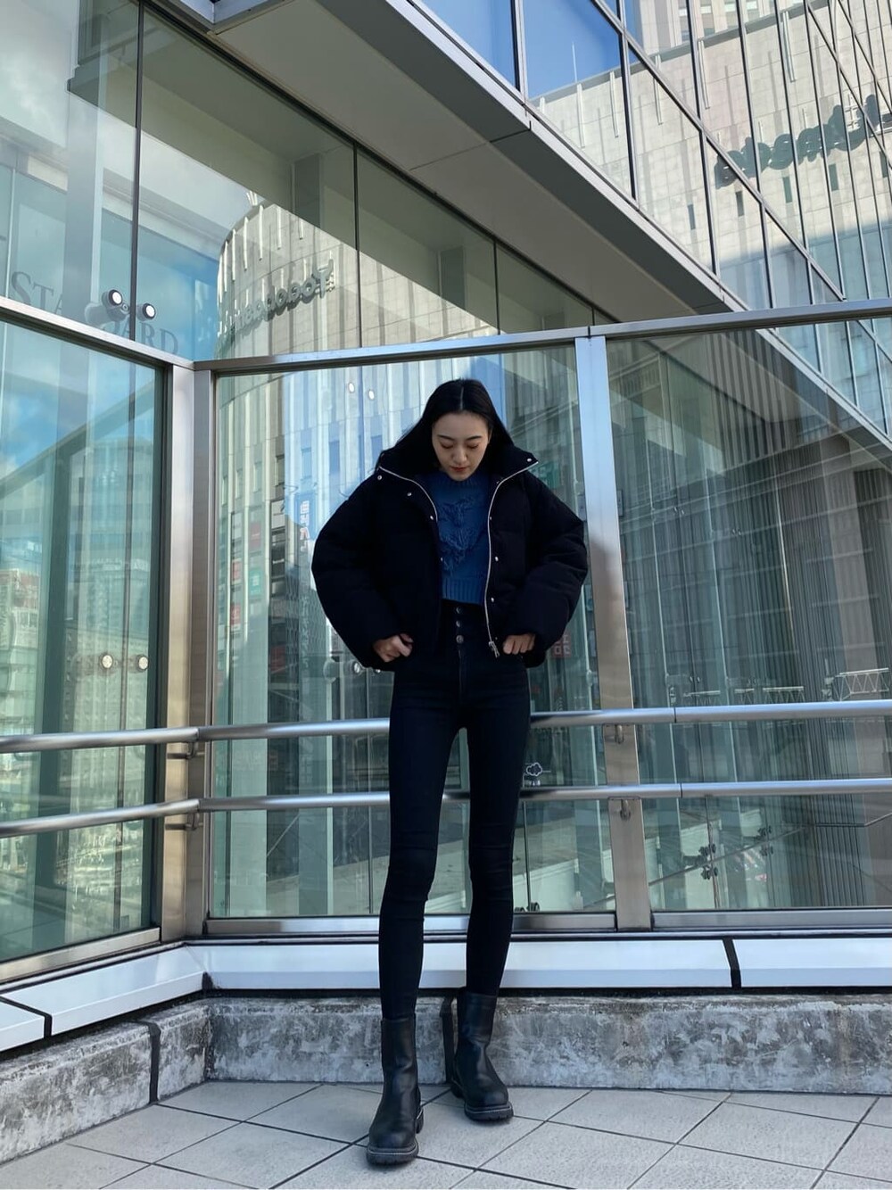 ブラック系のデニムパンツ、ブラック系のダウンジャケット/コート、ブルー系のニット/セーターを着用したレディースの冬コーディネートの2枚目の写真