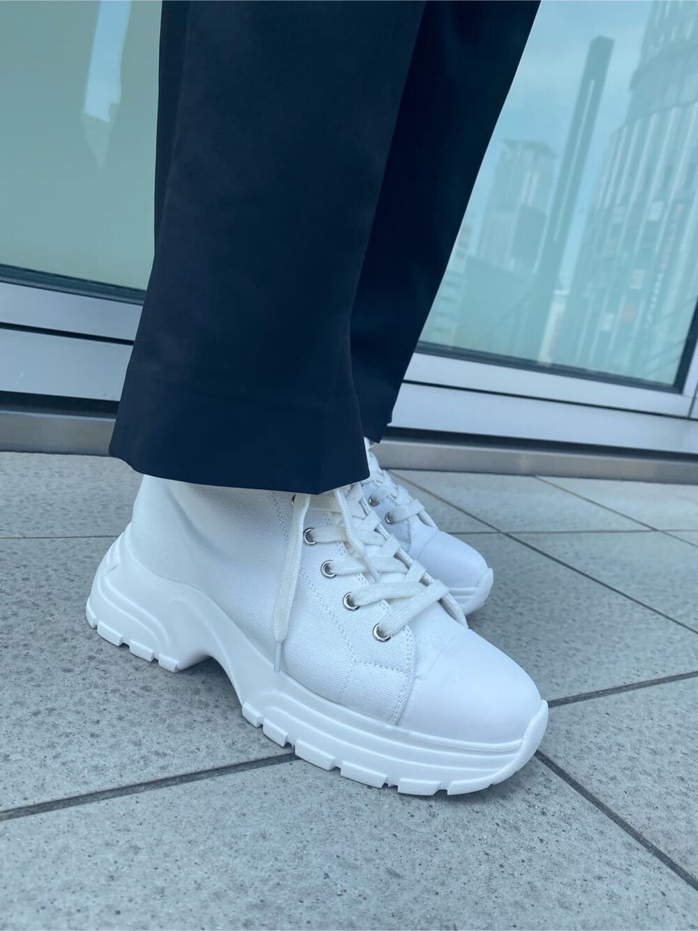 ホワイト系のスニーカー、ブラック系のベスト、ブラック系のその他パンツを着用したレディースの夏コーディネートの9枚目の写真