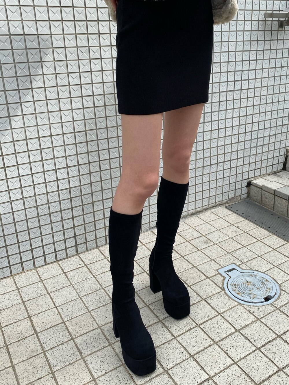 ブラック系のワンピース、ホワイト系のブルゾン、ブラック系のブーツを着用したレディースの冬コーディネートの8枚目の写真