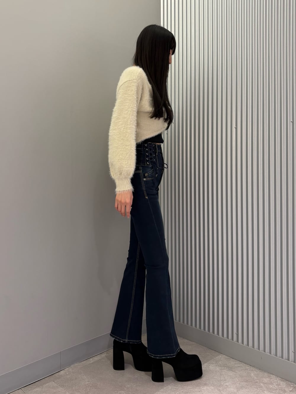 ブルー系のデニムパンツ、ブラック系のキャミソール、ホワイト系のニット/セーターを着用したレディースの秋コーディネートの3枚目の写真