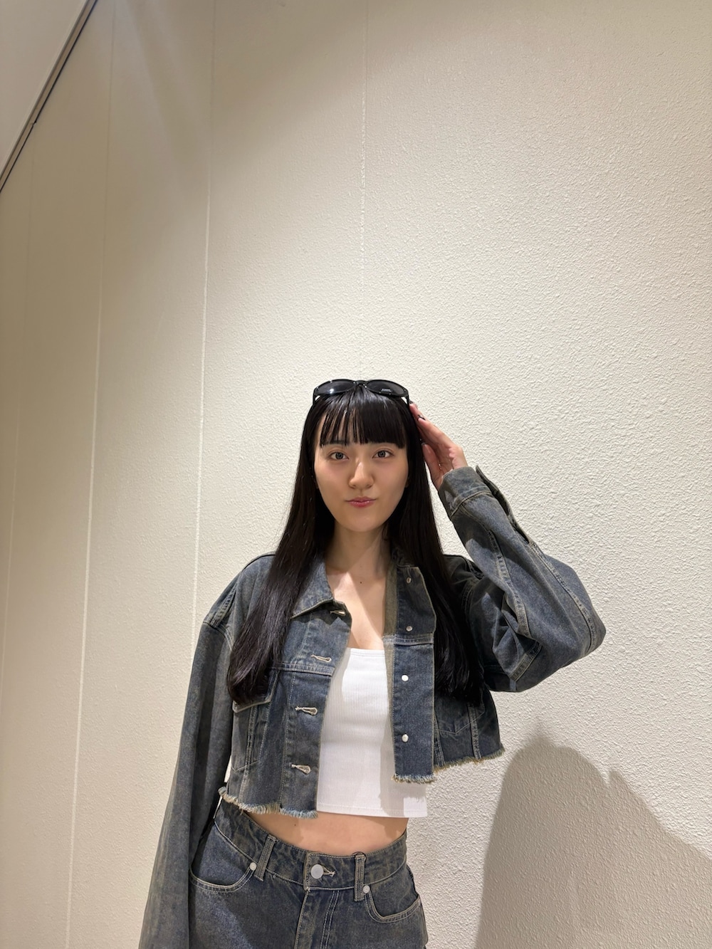 ブルー系のスカート、ブルー系のデニムジャケット、ホワイト系のキャミソールを着用したレディースの夏コーディネートの6枚目の写真