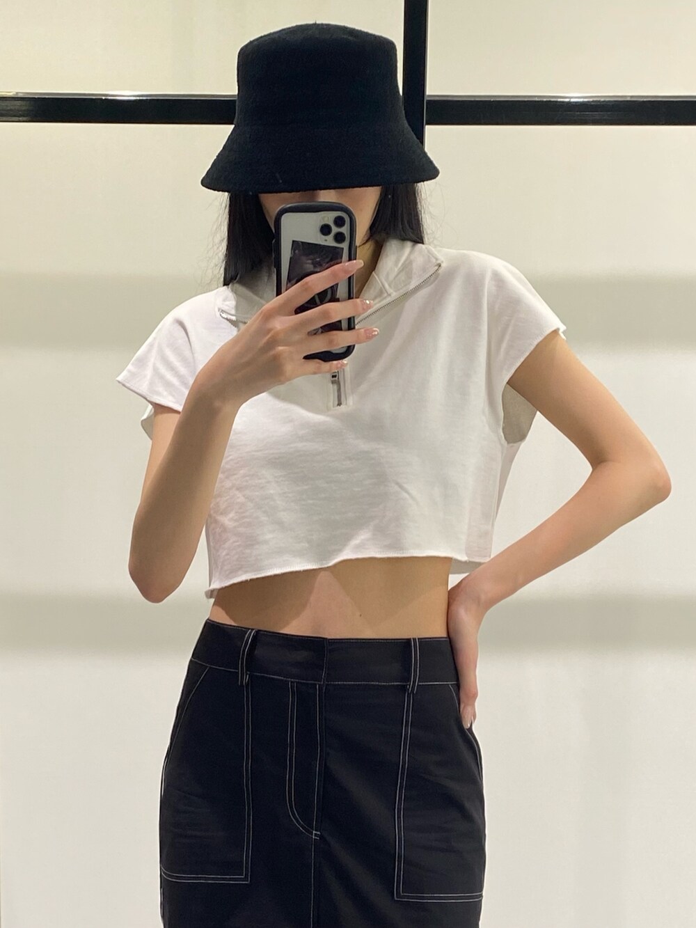 ブラック系のスカート、ホワイト系のTシャツ/カットソー、ブラック系のサンダルを着用したレディースの夏コーディネートの2枚目の写真
