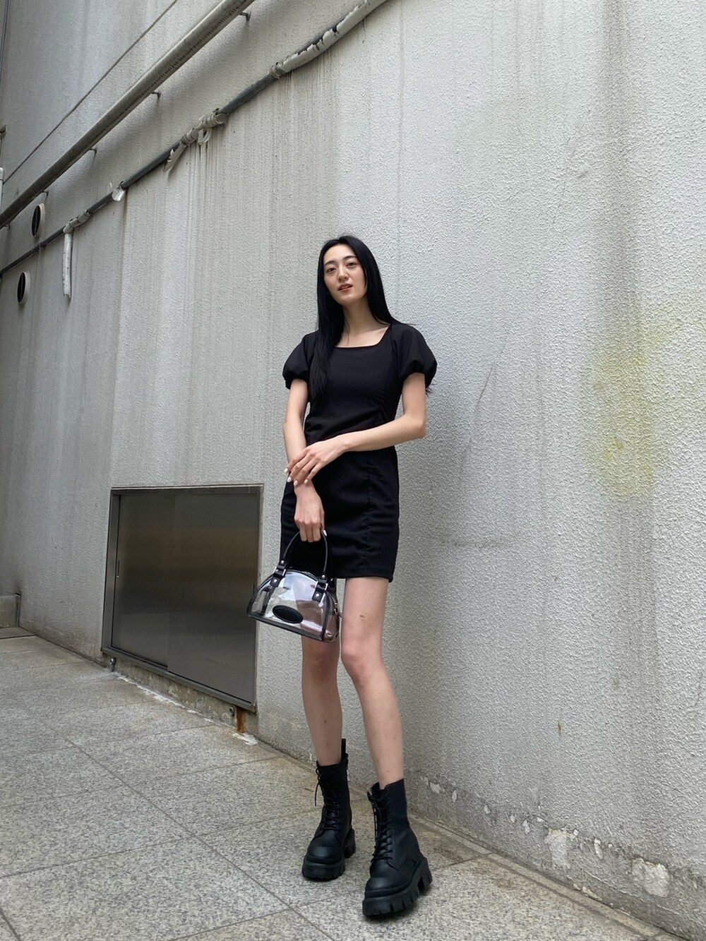 ブラック系のワンピース、ブラック系のブーツ、その他のハンドバッグを着用したレディースの春コーディネートの2枚目の写真