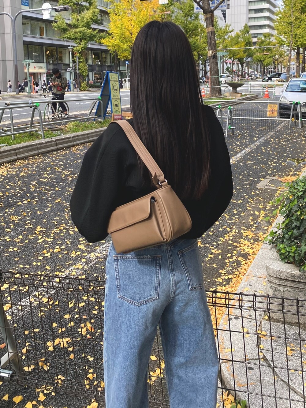 ブルー系のデニムパンツ、ブラック系のブーツ、ブラウン系のハンドバッグを着用したレディースの秋コーディネートの5枚目の写真