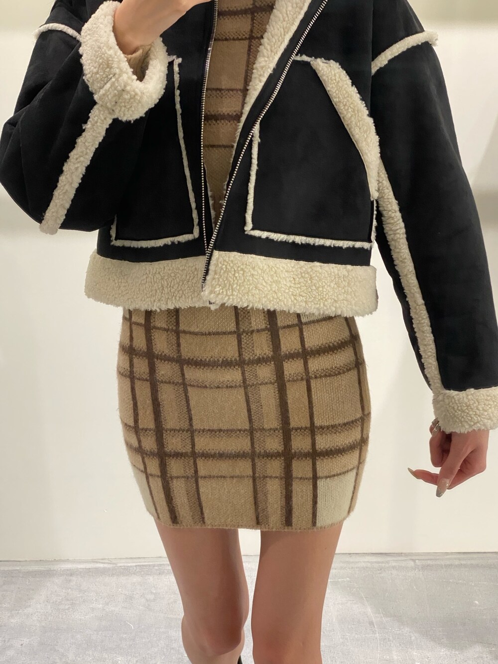 ベージュ系のスカート、ベージュ系のニット/セーター、ブラック系のブーツを着用したレディースの冬コーディネートの7枚目の写真