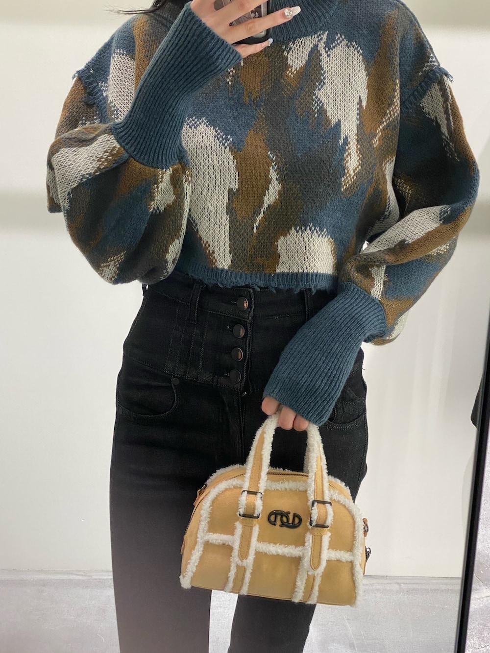 ベージュ系のハンドバッグ、ブラック系のデニムパンツ、ブルー系のニット/セーターを着用したレディースの秋コーディネートの3枚目の写真