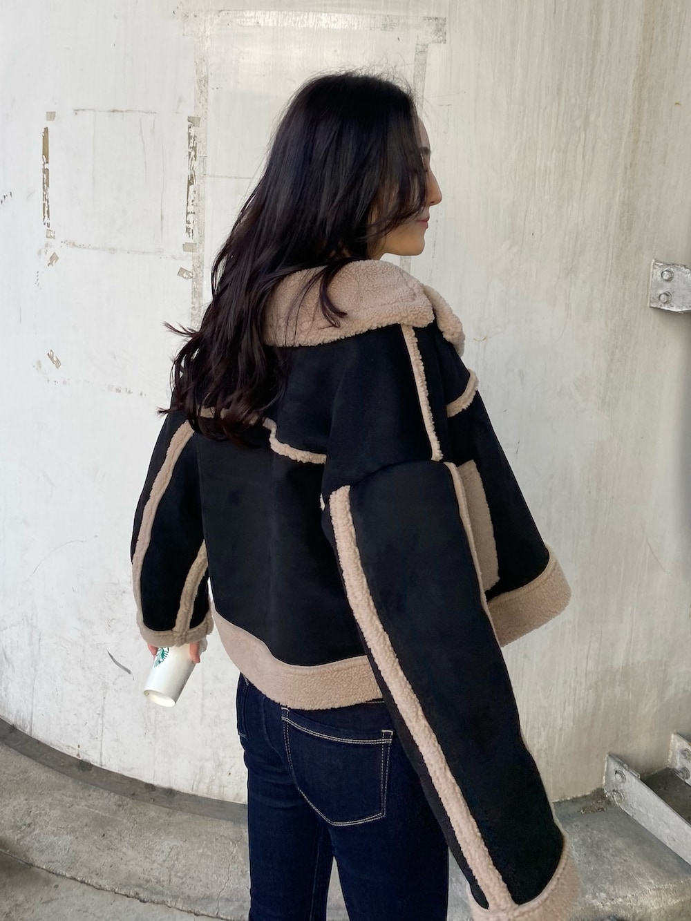 ブルー系のデニムパンツ、ブラック系のムートンコート、ホワイト系のニット/セーターを着用したレディースの秋コーディネートの6枚目の写真