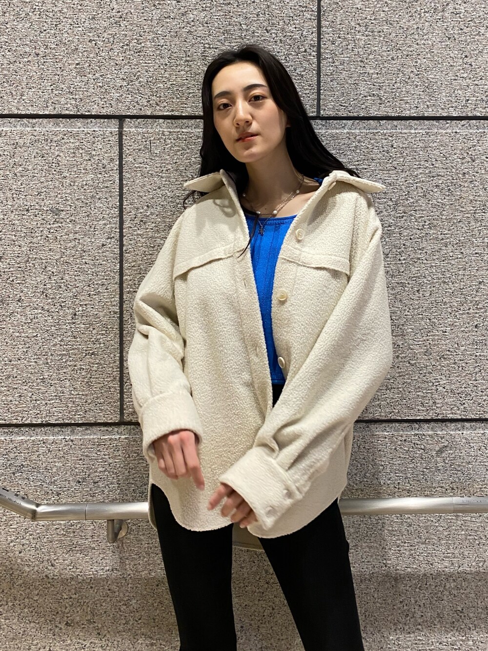 ホワイト系のブルゾン、ブルー系のニット/セーター、ブラック系のデニムパンツを着用したレディースの冬コーディネートの6枚目の写真