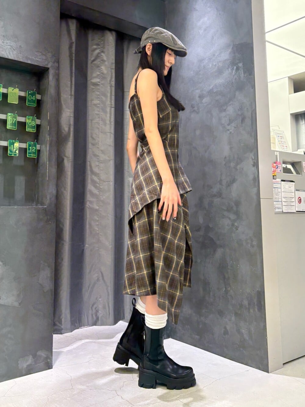 グリーン系のワンピース、ブラック系のブーツ、グレー系のハンチング/ベレー帽を着用したレディースの夏コーディネートの3枚目の写真