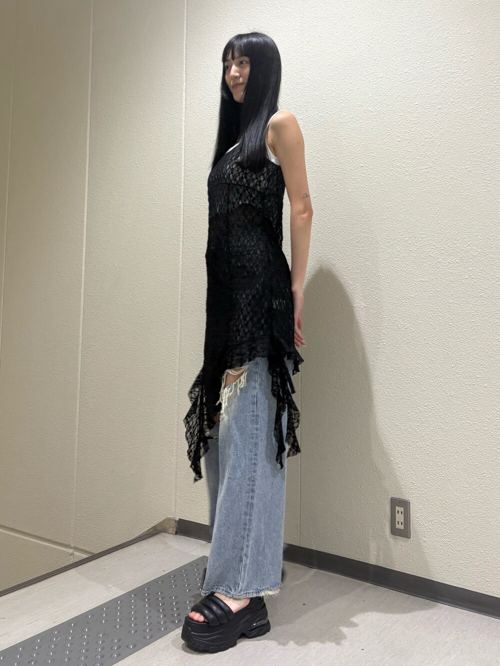 ホワイト系のニット/セーター、ブラック系のワンピース、ブルー系のデニムパンツを着用したレディースの夏コーディネートの3枚目の写真