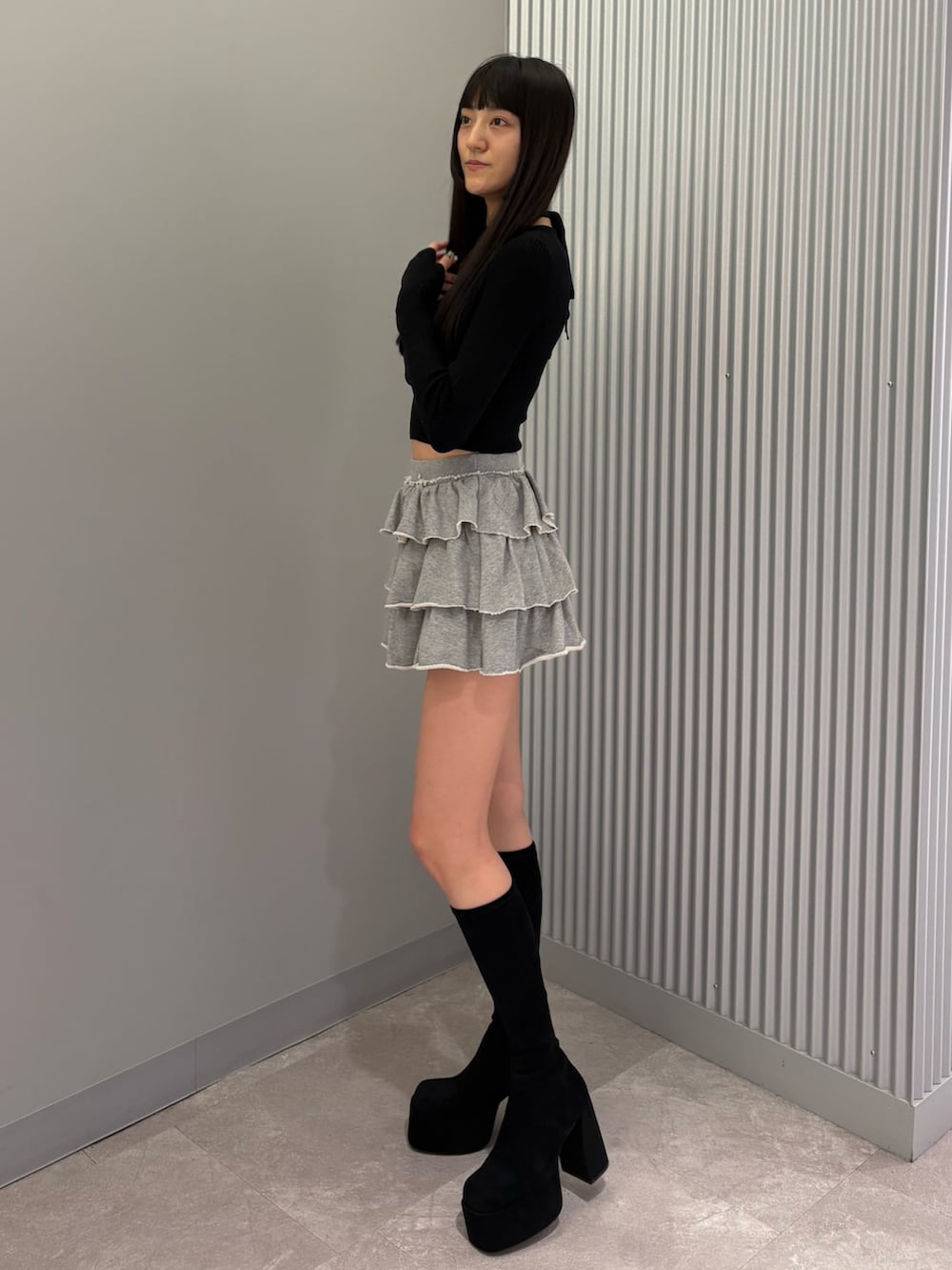 グレー系のスカート、ブラック系のニット/セーター、ブラック系のブーツを着用したレディースの秋コーディネートの2枚目の写真