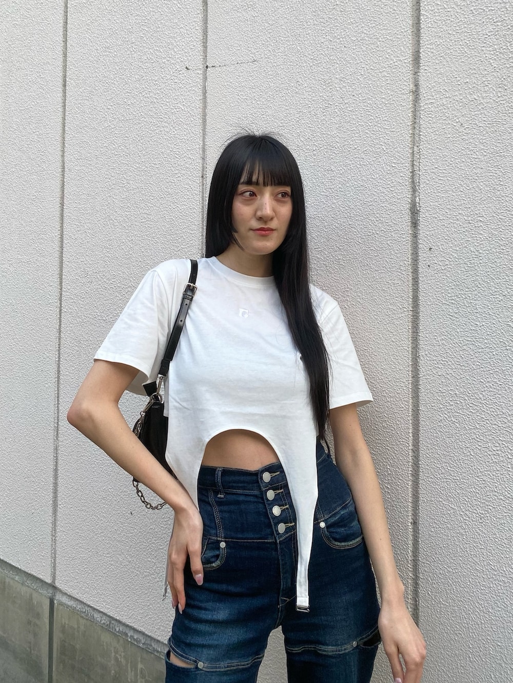 ブルー系のデニムパンツ、ブラック系のショルダーバッグ、ホワイト系のTシャツ/カットソーを着用したレディースの春コーディネートの4枚目の写真