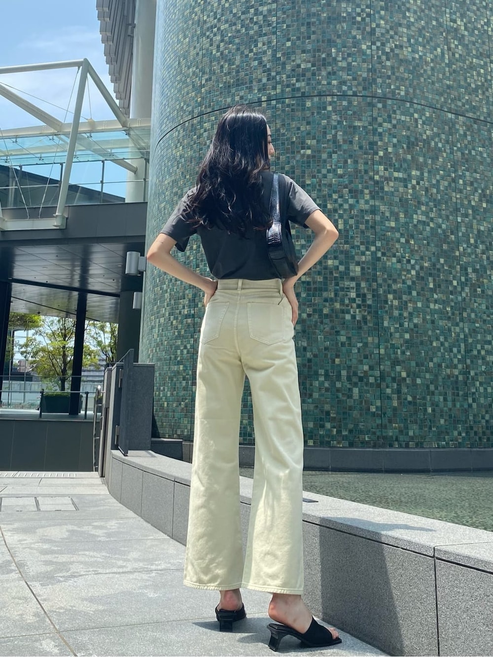 ホワイト系のデニムパンツ、ブラック系のサンダル、ブラック系のハンドバッグを着用したレディースの夏コーディネートの4枚目の写真