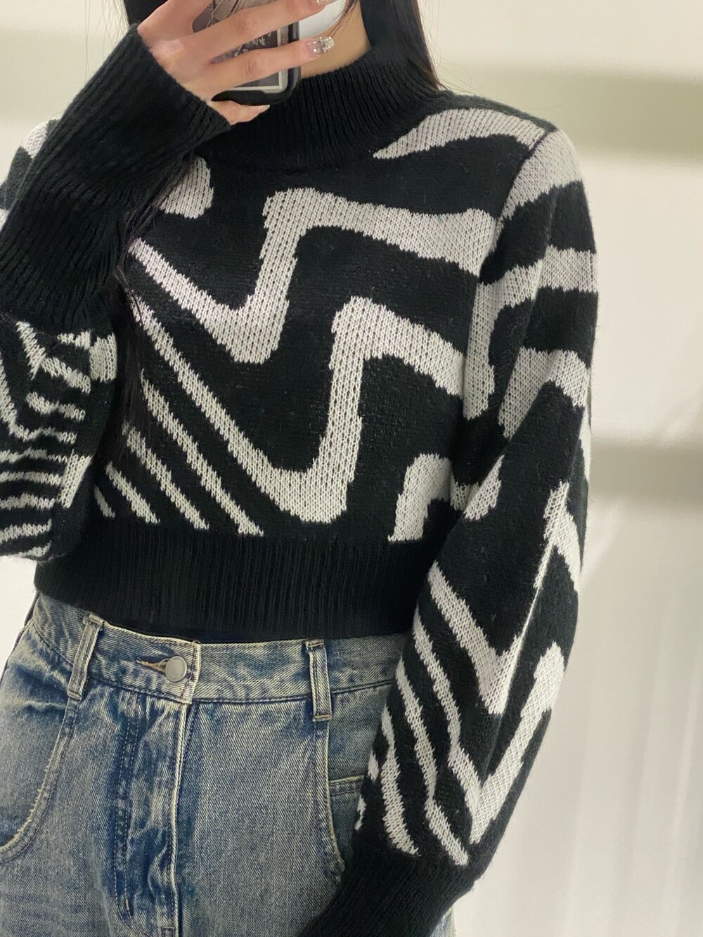 ブルー系のデニムパンツ、ブラック系のニット/セーター、ブラック系のブーツを着用したレディースの冬コーディネートの4枚目の写真