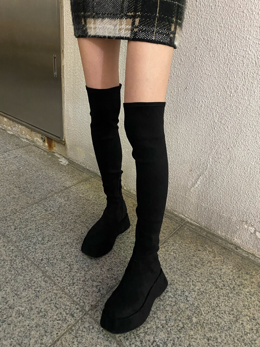 ブラック系のスカート、ブラック系のニット/セーター、ブラック系のブーツを着用したレディースの冬コーディネートの7枚目の写真