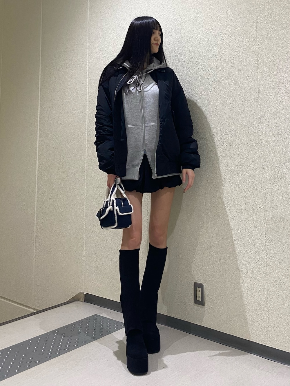 グレー系のパーカー、ブラック系のブルゾン、ブルー系のハンドバッグを着用したレディースの秋コーディネートの4枚目の写真
