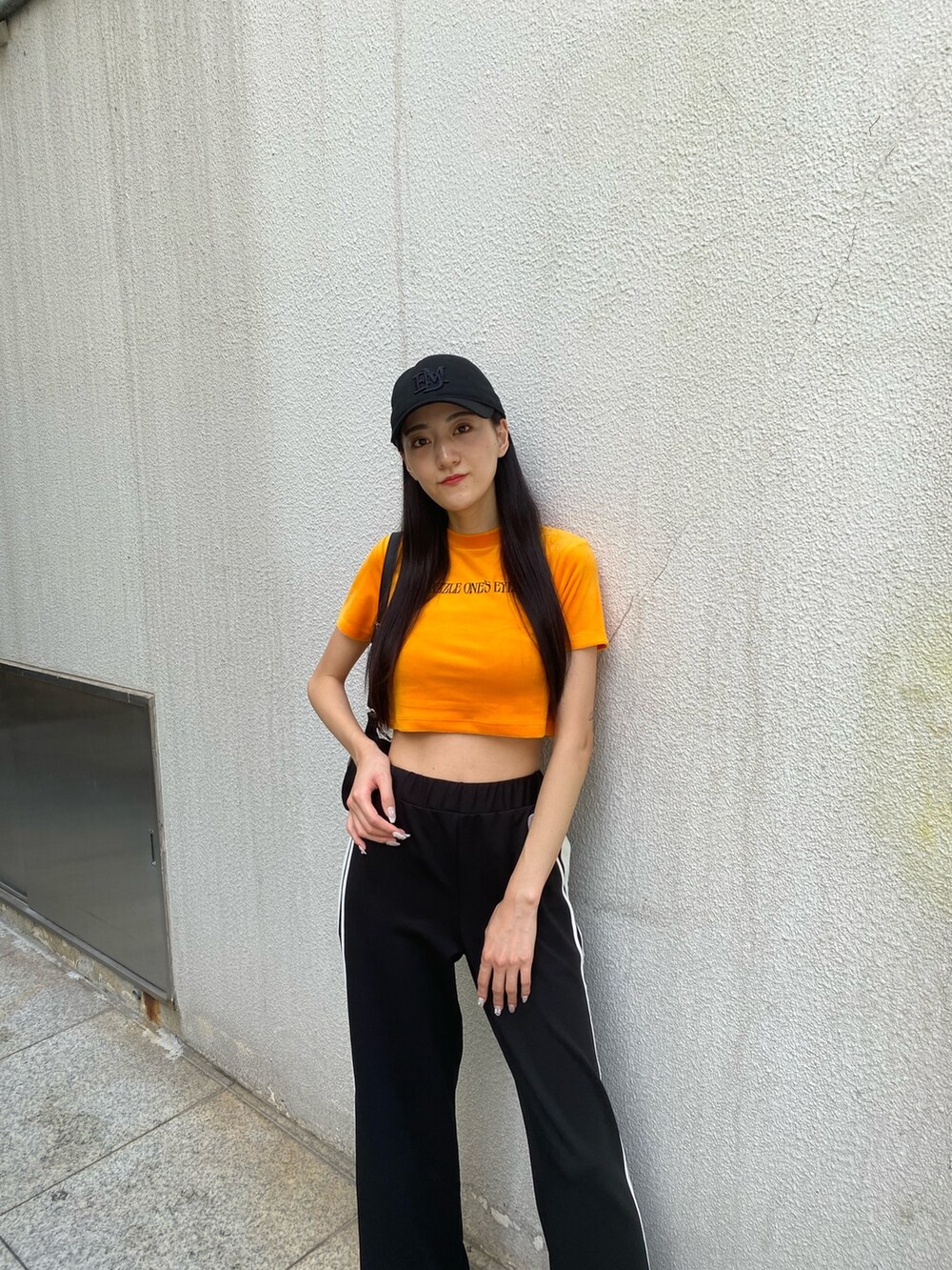 ブラック系のその他パンツ、ブラック系のハンドバッグ、オレンジ系のTシャツ/カットソーを着用したレディースの夏コーディネートの7枚目の写真