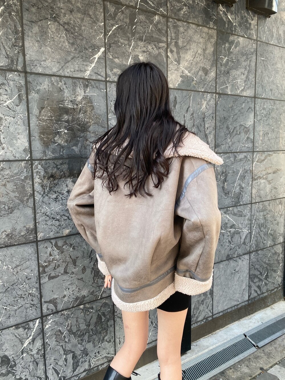 グレー系のブルゾン、ブラック系のワンピース、ブラック系のブーツを着用したレディースの冬コーディネートの5枚目の写真