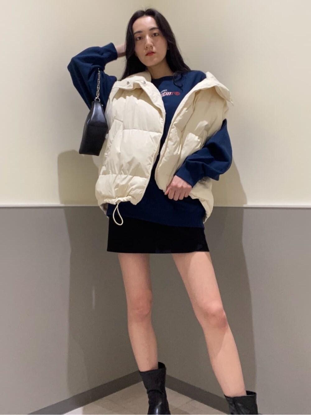 ブラック系のスカート、ホワイト系のダウンベスト、ブルー系のスウェットを着用したレディースの秋コーディネートの4枚目の写真