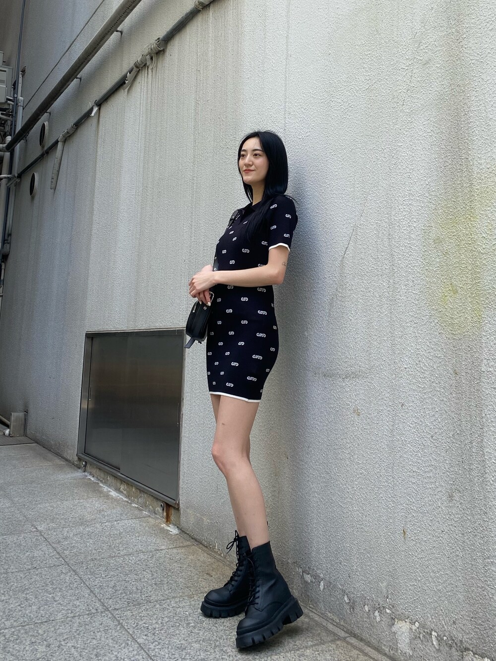 ブラック系のワンピース、ブラック系のブーツ、ブラック系のショルダーバッグを着用したレディースの春コーディネートの4枚目の写真