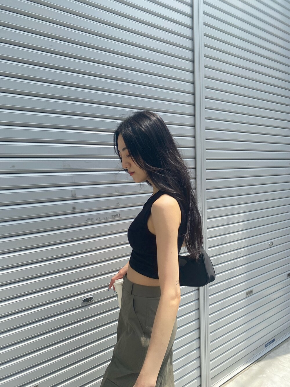ベージュ系のカーゴパンツ、ブラック系のタンクトップ、ブラック系のハンドバッグを着用したレディースの夏コーディネートの6枚目の写真