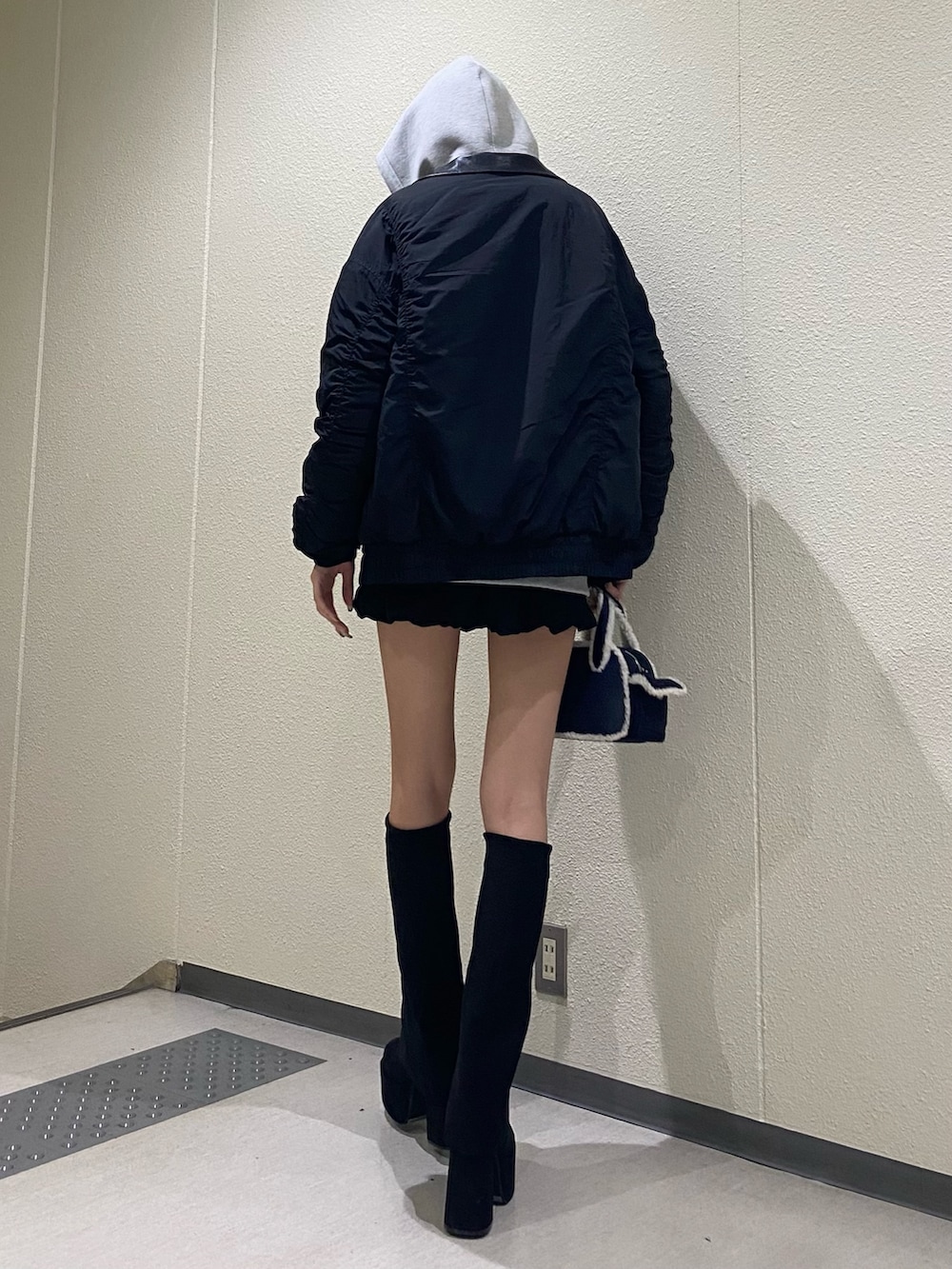 グレー系のパーカー、ブラック系のブルゾン、ブルー系のハンドバッグを着用したレディースの秋コーディネートの5枚目の写真