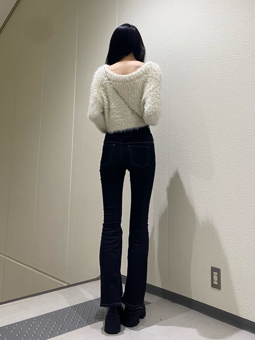 ホワイト系のニット/セーター、ブラック系のブーツ、ブラック系のデニムパンツを着用したレディースの冬コーディネートの4枚目の写真