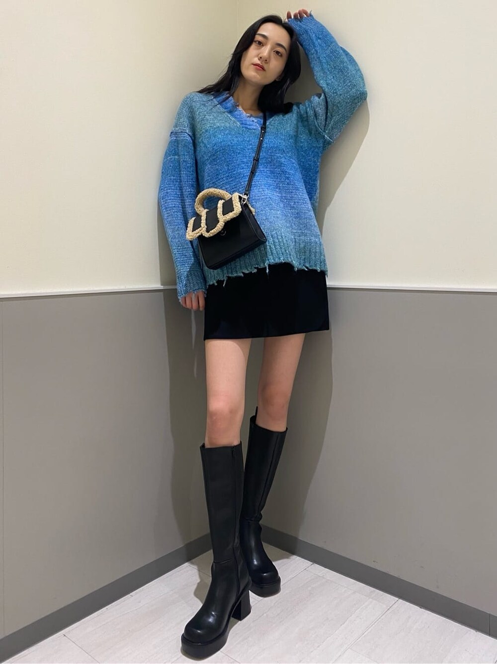 ブラック系のブーツ、ブラック系のスカート、ブルー系のニット/セーターを着用したレディースの秋コーディネートの2枚目の写真