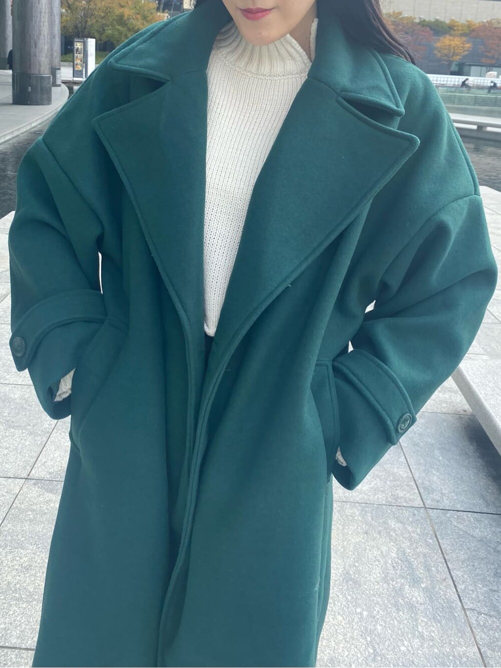 ブラック系のデニムパンツ、ホワイト系のニット/セーター、グリーン系のチェスターコートを着用したレディースの秋コーディネートの4枚目の写真