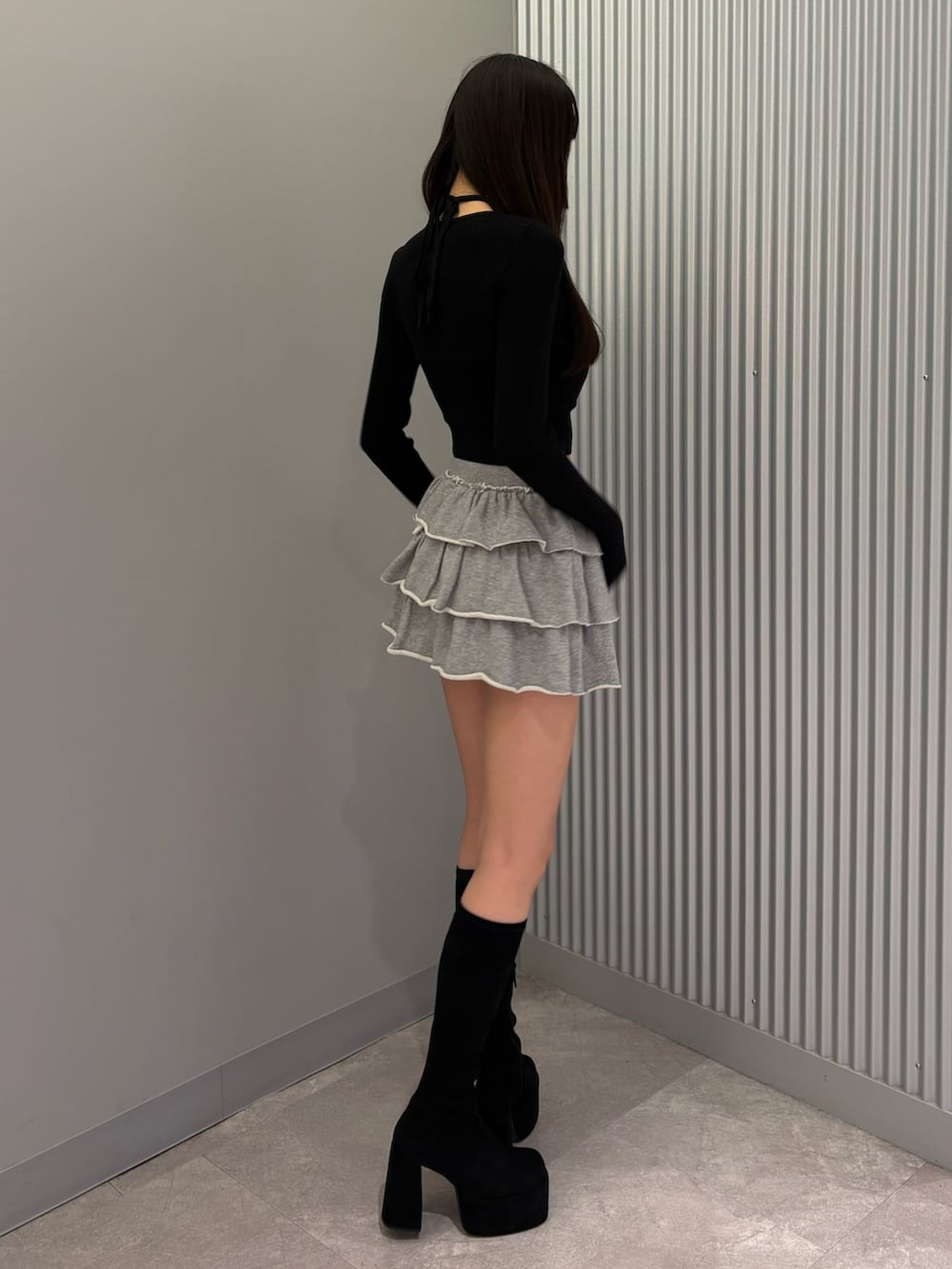 グレー系のスカート、ブラック系のニット/セーター、ブラック系のブーツを着用したレディースの秋コーディネートの4枚目の写真