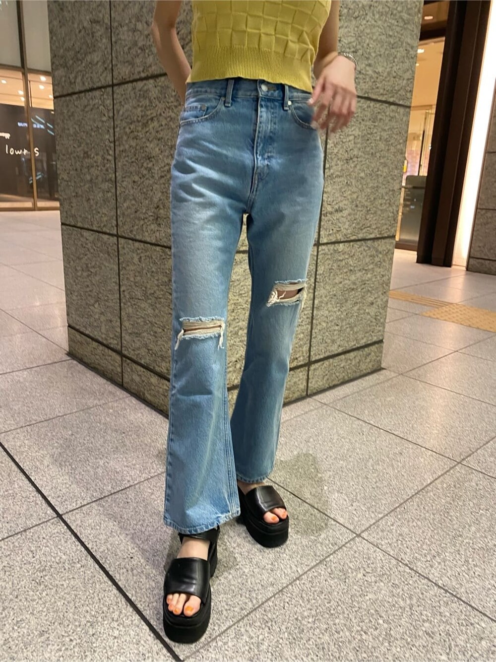 イエロー系のタンクトップ、ブルー系のデニムパンツ、ブラック系のサンダルを着用したレディースの夏コーディネートの3枚目の写真