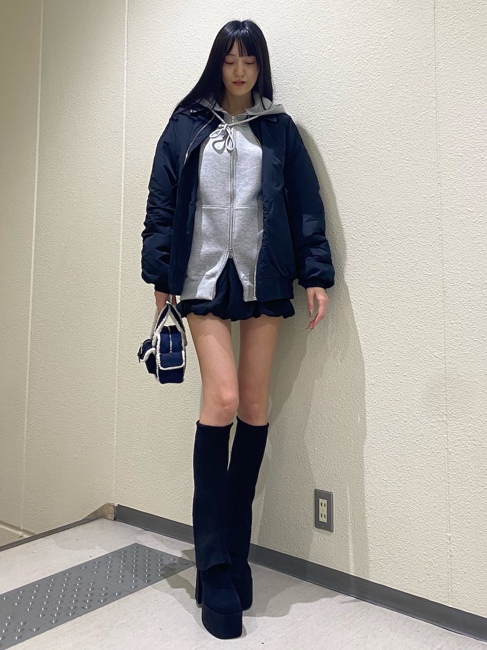 グレー系のパーカー、ブラック系のブルゾン、ブルー系のハンドバッグを着用したレディースの秋コーディネートの2枚目の写真