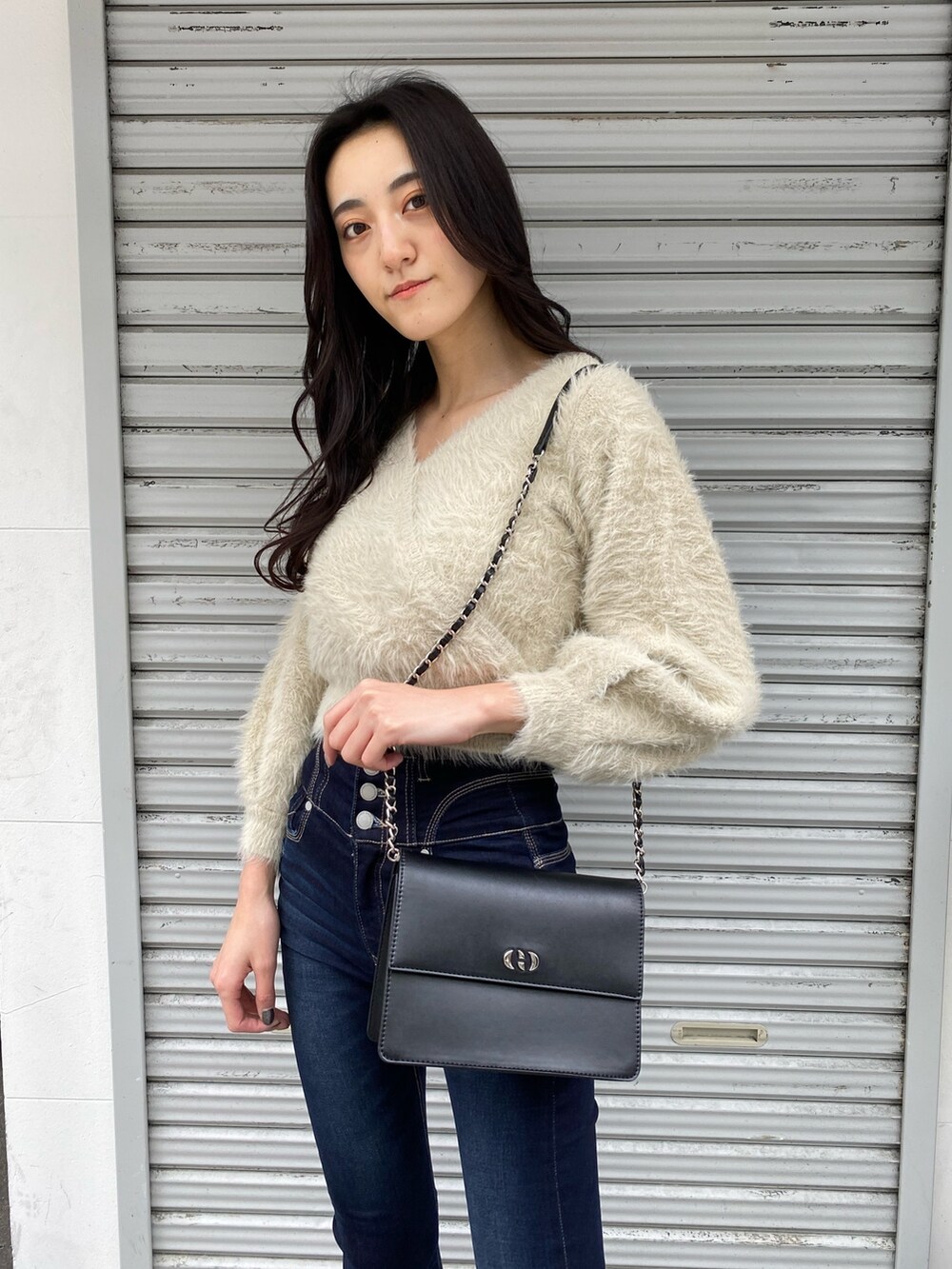 ブラック系のハンドバッグ、ブルー系のデニムパンツ、ホワイト系のニット/セーターを着用したレディースの冬コーディネートの5枚目の写真