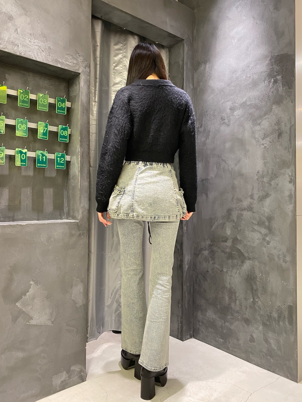 ブルー系のデニムパンツ、ブラック系のニット/セーター、ブラック系のブーツを着用したレディースの秋コーディネートの4枚目の写真