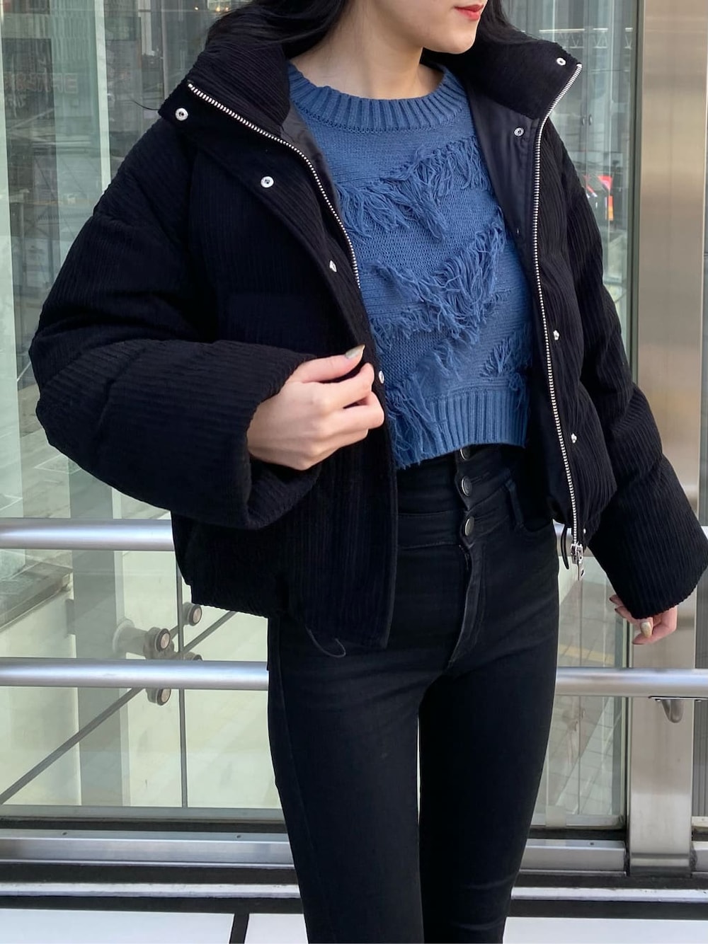 ブラック系のデニムパンツ、ブラック系のダウンジャケット/コート、ブルー系のニット/セーターを着用したレディースの冬コーディネートの4枚目の写真