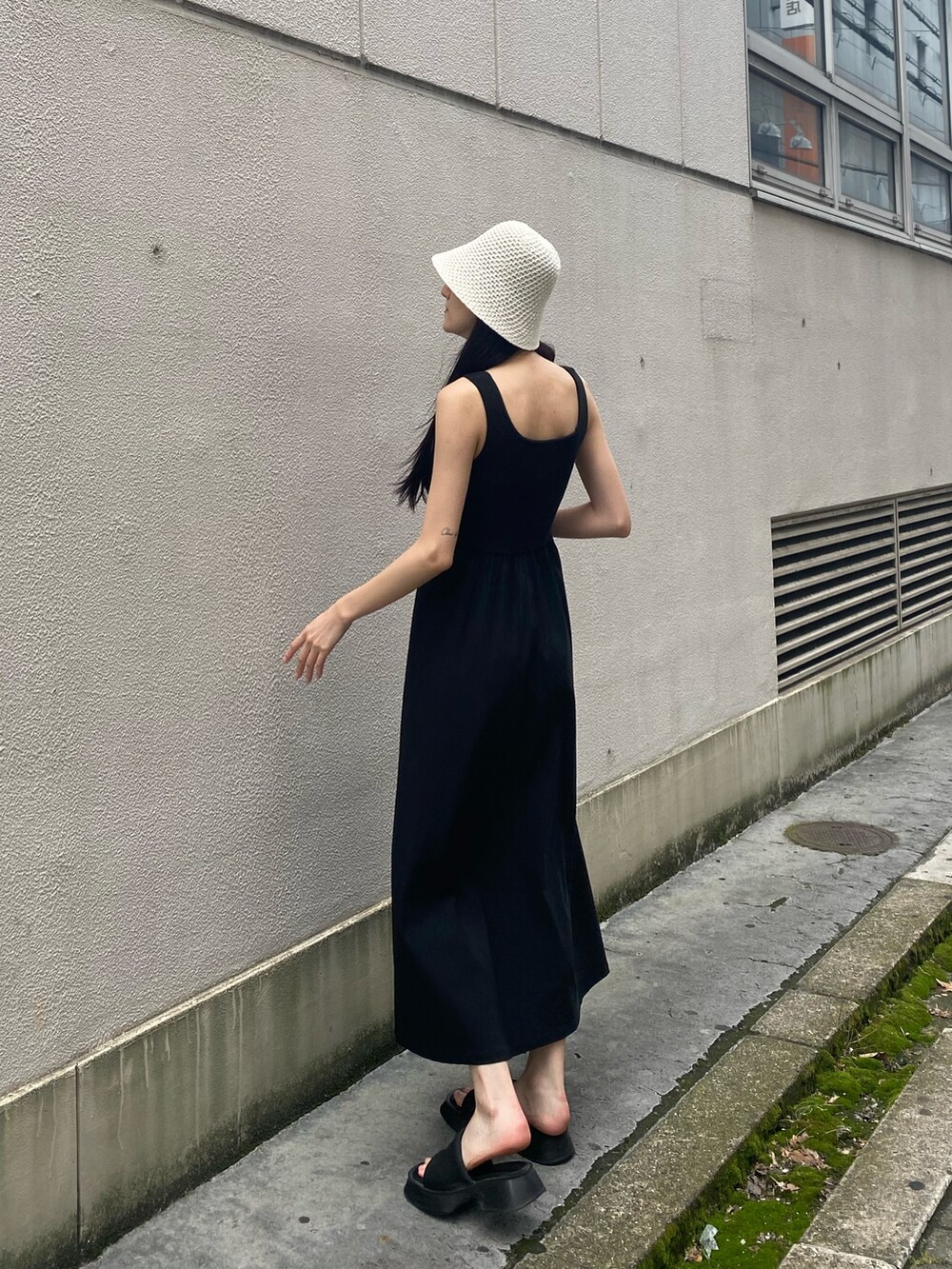 ブラック系のワンピース、ブラック系のサンダル、ホワイト系のハットを着用したレディースの夏コーディネートの5枚目の写真