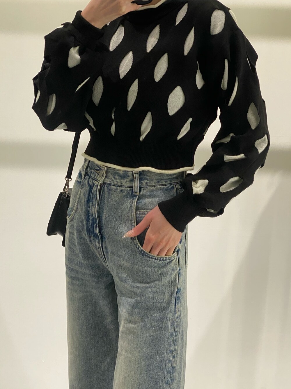 ブルー系のデニムパンツ、ブラック系のニット/セーター、ブラック系のショルダーバッグを着用したレディースの冬コーディネートの2枚目の写真