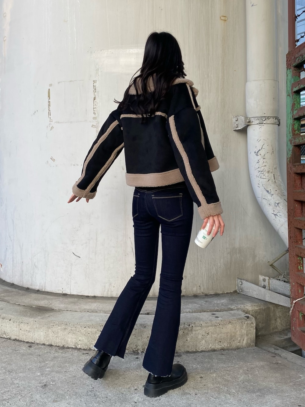 ブルー系のデニムパンツ、ブラック系のムートンコート、ホワイト系のニット/セーターを着用したレディースの秋コーディネートの3枚目の写真