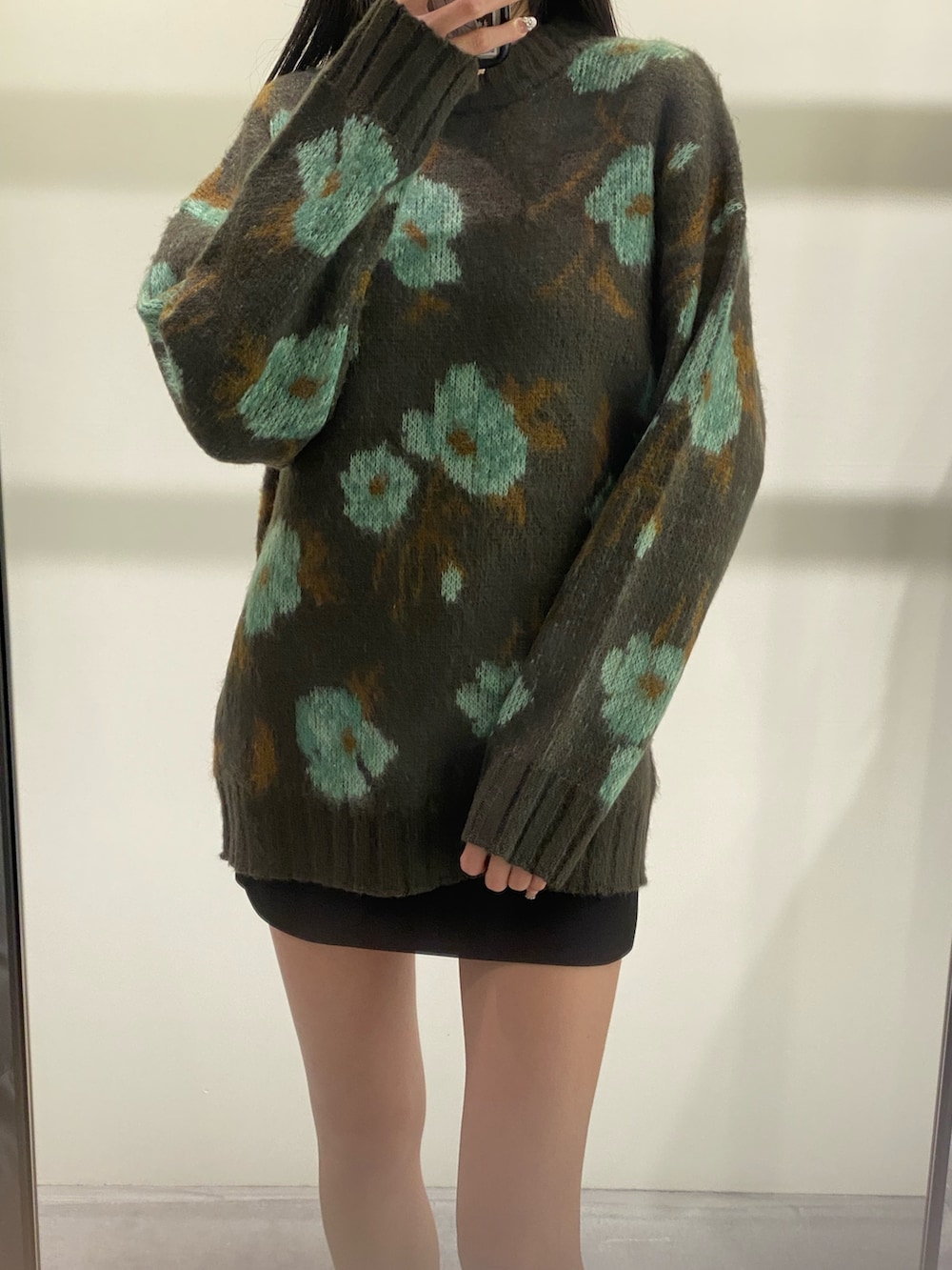 グリーン系のニット/セーター、ブラック系のスカート、ブラック系のブーツを着用したレディースの秋コーディネートの2枚目の写真