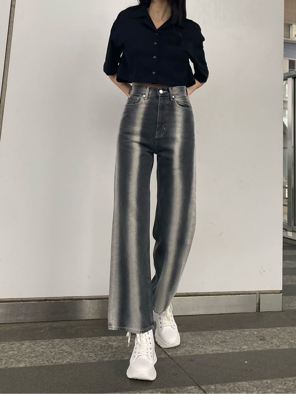 ブラック系のデニムパンツ、ブラック系のシャツ/ブラウス、ホワイト系のスニーカーを着用したレディースの春コーディネートの2枚目の写真