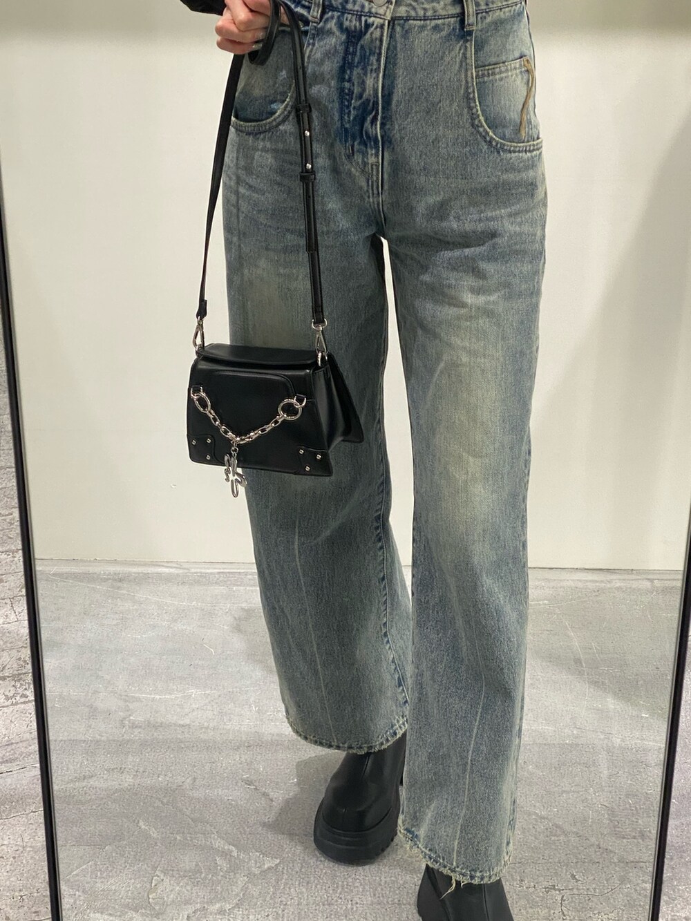 ブルー系のデニムパンツ、ブラック系のニット/セーター、ブラック系のショルダーバッグを着用したレディースの冬コーディネートの6枚目の写真