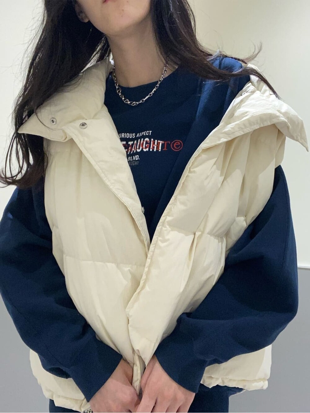 ブラック系のスカート、ホワイト系のダウンベスト、ブルー系のスウェットを着用したレディースの秋コーディネートの5枚目の写真